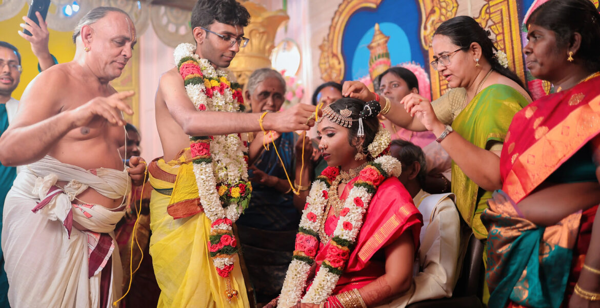 Groom gently placing flowers on bride's head during Kapila & Kokila's Brahmin Wedding Photoshoot. The Art of Storytelling: A Coimbatore Wedding Photographer's Guide